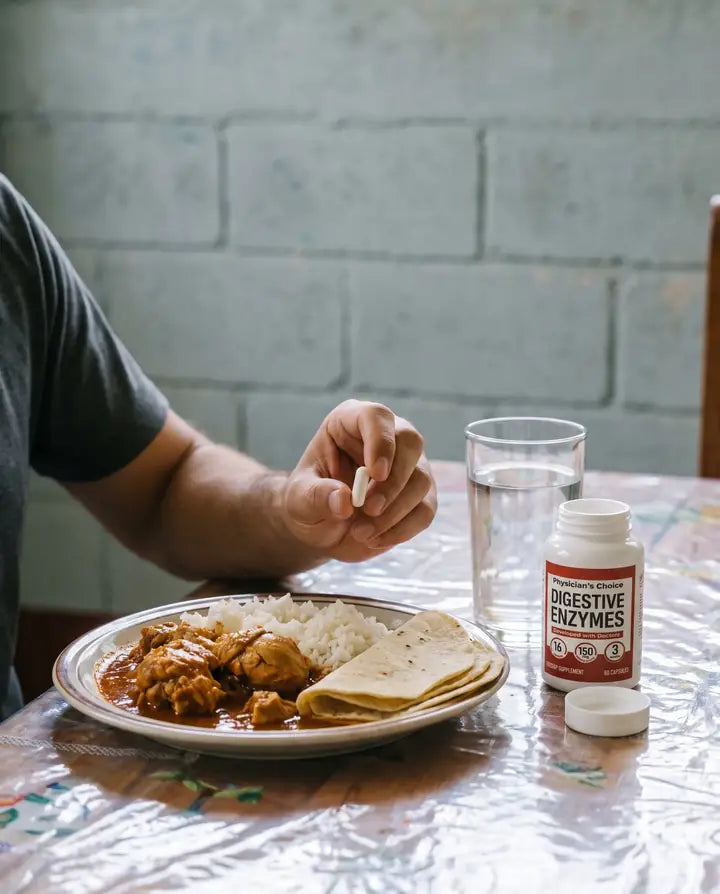 Mano tomando una cápsula junto al plato del almuerzo